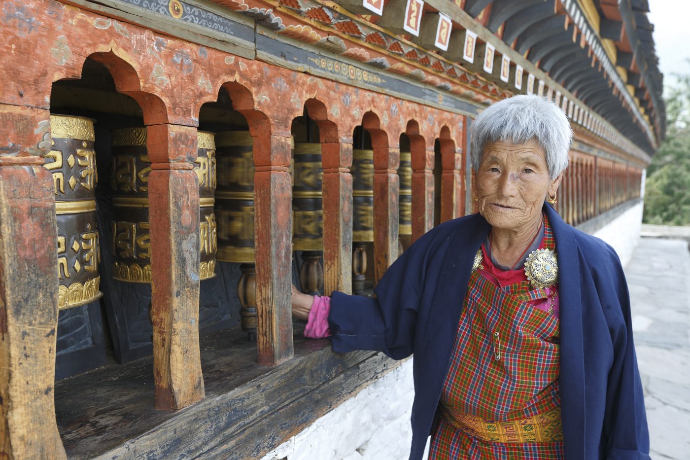 An elder turning prayer wheels along a monastery kora