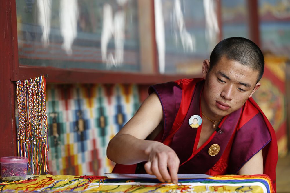 A young monk preparing blessing cords for visitors