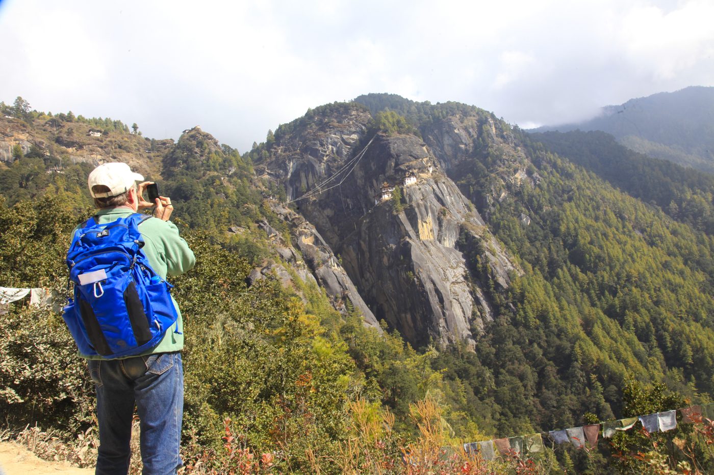 A traveller photographing Paro Taktsang, the Tiger's Nest Monastery